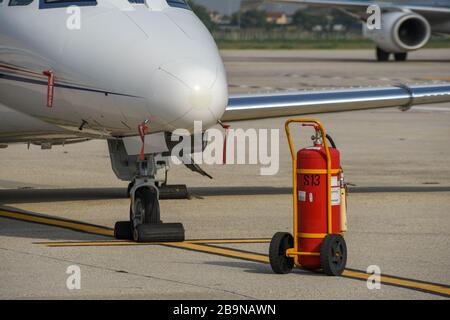 VERONA, ITALIEN - SEPTEMBER 2018: Feuerlöscher auf einem Rollwagen an der Nase eines Executive-Jets am Flughafen Verona. Stockfoto