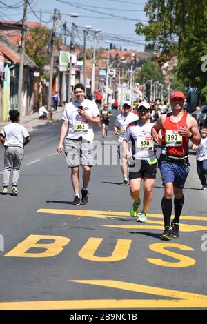 Marathon in der Belgrader Straße. Athleten laufen, und ein Junge treibt einen Tross zwischen ihnen Stockfoto