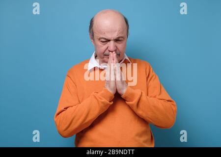 Ausdrucksstarker, gut aussehender älterer Mann, der um Hilfe und Zukunft betet. Stockfoto