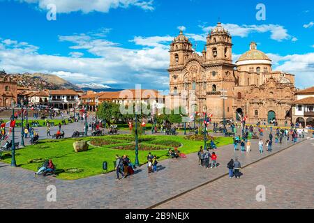 Der Plaza de Armas Hauptplatz von Cusco mit nicht erkennbaren Menschen an einem Sommertag mit der Compania de Jesus Kirche im Hintergrund, Peru. Stockfoto