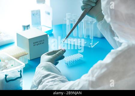 Die medizinische Technologie in Schutzanzug, Maske und Brille arbeitet mit Patienten-Tupfer zusammen, um eine bestimmte Region des 2019-nCoV-Virus zu erkennen, der Covid-19-Virus-Pneumone verursacht Stockfoto