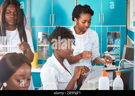 Weibliche afrikanische Medizinstudenten, junge Absolventen in der Forschung, medizinisches Testlabor, das verschiedene Tests an Proben durchführt. Mikroskopische Analysenbiopsie, pcr Stockfoto