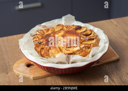Frisch gebackene apfelkuchen zu Hause im Backofen in der Küche. Hausgemachtes Backen von Apple Charlotte. Veganer Kuchen in einer Backform Stockfoto