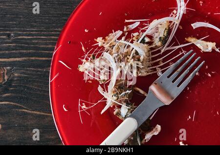 Fischknochen auf einer einzigen roten Platte. Nahaufnahme. Holztisch Stockfoto