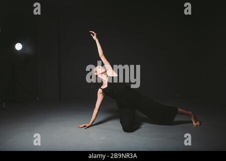 Porträt einer schönen Frau, die auf schwarzem Hintergrund tanzt. Ballett und zeitgenössische Tänzerin, die auf dunkler Kulisse tanzt. Zeitgenössische Kunst Kunststoff und Stockfoto