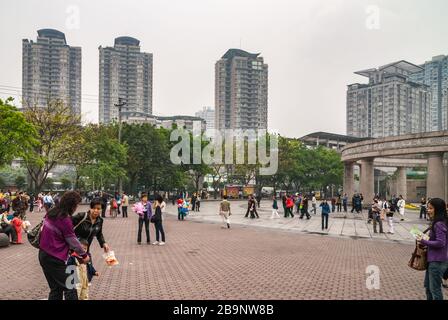 Chongqing, China - 9. Mai 2010: Viele Menschen auf dem Platz vor dem Zoo, von dem die runde Eingangskonstruktion aus braunem Stein zu sehen ist. S Stockfoto