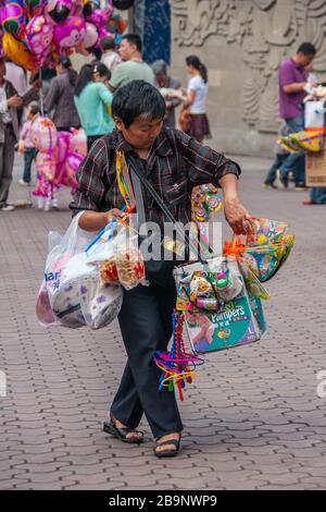 Chongqing, China - 9. Mai 2010: Außerhalb des Zoos oder Tierparks. Nahaufnahme des männlichen ambulanten Anbieters, der Snacks und bunte Spielzeuge auf dem Platz verkauft. Stockfoto