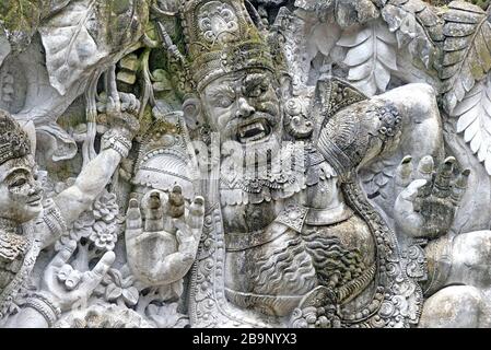 Steinmauer mit balinesischen Dämonen und Göttern, Heros der hinduistischen Mythen. Stockfoto
