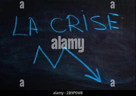 Das Wort "Krise" auf französisch. Die Aufschrift "Crisis" auf der Tafel. Blaue Kreide Stockfoto