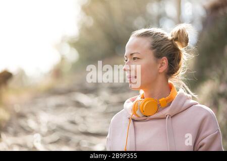 Porträt einer schönen Sportfrau mit Hoodie und Kopfhörern während des Trainings im Freien. Stockfoto