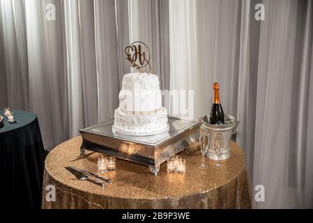 High-Angle-Aufnahme einer weißen Hochzeitstorte und ein Korb mit einer Champagnerflasche auf dem Tisch Stockfoto