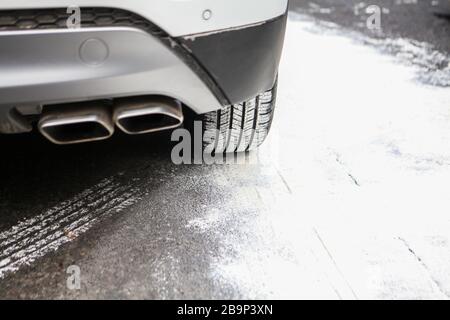 Auto rechts hinten auf einer verschneiten Straße mit einer Reifenspur Stockfoto