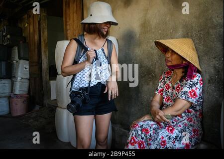 Ein weiblicher Tourist aus Ho-Chi-Minh-Stadt im Gespräch mit einer einheimischen Frau in Bến đò Duy Hải, Vietnam Stockfoto