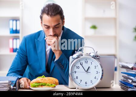 Junge Angestellte, die am Arbeitsplatz frühstücken Stockfoto