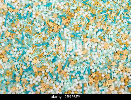 Hintergrund mit türkisfarbenen Süßigkeiten, weißen und türkisfarbenen Kugeln und goldenen Sternen. Flacher Lay Draufsicht von oben. Stockfoto