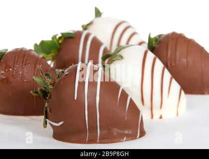 Nahaufnahme von riesigen Erdbeeren, die in weiße und Milchschokolade getaucht sind und mit gegensätzlicher Weiß- und Milchschokolade getrindert sind. Stockfoto