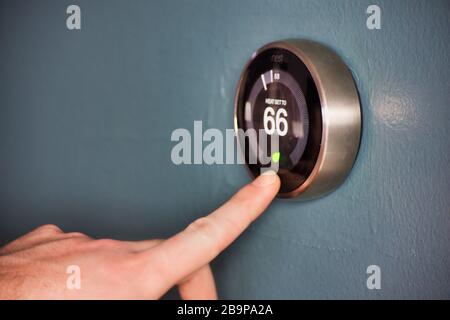 Intelligenter Thermostat mit Handbetrieb spart Geld. Aktivieren des Energiesparmodus. Stockfoto