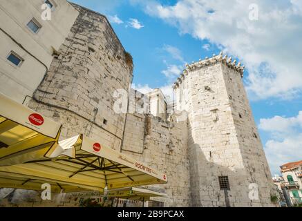 Ein Straßencafé befindet sich unter einer alten Mauer und einem Turm am Obstplatz im Diokletian-Palast in der Altstadt von Split Kroatien. Stockfoto