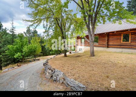 Rustikale Blockhütte in ländlicher Bergkulisse mit Landschaftsfelsen und Hängematte zwischen zwei Bäumen in den Bergen der USA. Stockfoto