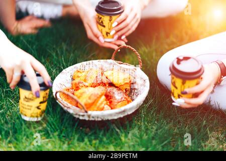 Sommerzeit: Picknick auf dem Gras - Kaffee in Händen und Croissants, Saft und Beeren. Selektiver Fokus. Freunde Stockfoto