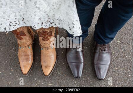 Alternative Brautpaar am Hochzeitstag mit Cowboystiefeln Stockfoto