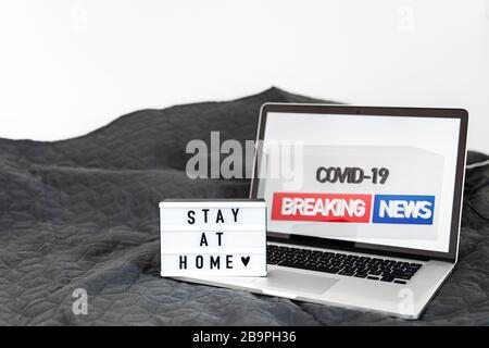 Leuchtkasten mit "Bleibe zu Hause"-Text auf Holzhintergrund. Flat-Lay-Covid-19-Angebot in Draufsicht Stockfoto