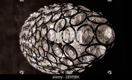 Funkelnde Skala mit kristallklaren runden Elementen im Inneren. Glänzende Oberfläche des Glaskronleuchters. Die moderne Lampentextur aus Glas sieht aus wie ein Disco-Ball. Stockfoto