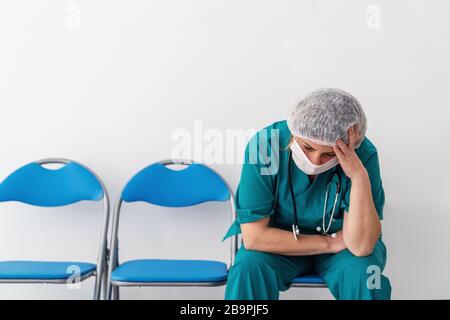 Frau Doktor sitzt und hat, Sorge, Frustration, Müdigkeit und anstrengende tiefe Gefühle Stockfoto