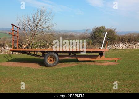 Gesessen geparkt in der Ecke eines Feldes sitzt dieser schwere Anhänger auf den Heuballen, die er normalerweise von Feld zu Hof transportiert. Stockfoto