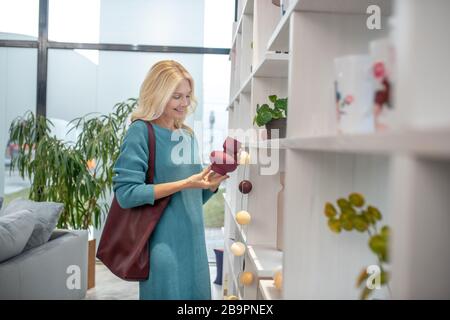 Frau mit einer kleinen Vase in den Händen in einem Laden. Stockfoto