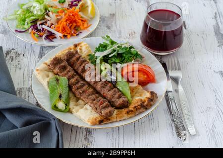 Traditionelles Adana Kebap mit Tomaten und Salat auf einem Fladenbrot als Draufsicht. Stockfoto