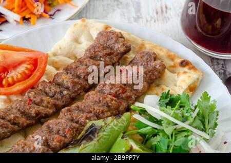 Traditionelles Adana Kebap mit Tomaten und Salat auf einem Fladenbrot als Draufsicht. Stockfoto