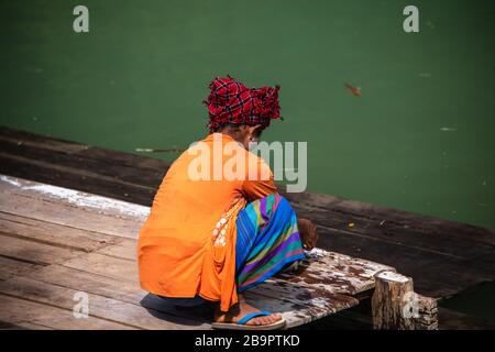 Die lokale Intha-Tribesfrau waschen Kleidung an einem Flussufer, dem Inle Lake, Myanmar. Rückansicht Porträt einer Frau vor Wasserhintergrund Stockfoto