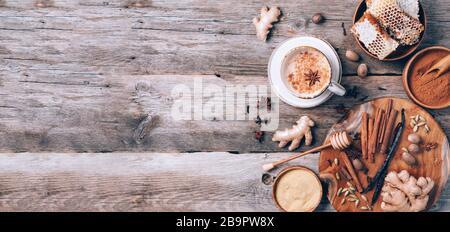 Tee mit Milch, Nelken, Ingwer, Kardamom, Zimt, Anis, Eile, Honig, Muskatnuss. Indischer Masala-Tee mit Gewürzen. Draufsicht, Kopierbereich. Antiviraler Bevera Stockfoto