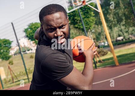 Aktivitäten Im Freien. Afrikanischer Mann läuft mit Ball auf dem Platz wütend Nahaufnahme Stockfoto