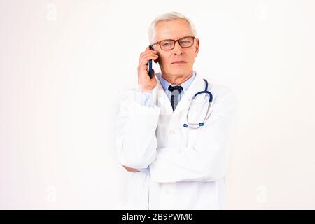 Portraitaufnahme eines männlichen Oberarztes mit dem Handy, während er mit seinem Patienten spricht. Isolierter weißer Hintergrund. Stockfoto