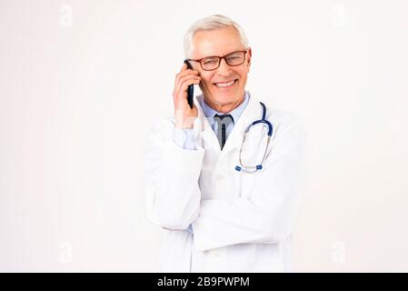 Portraitaufnahme eines männlichen Oberarztes mit dem Handy, während er mit seinem Patienten spricht. Isolierter weißer Hintergrund. Stockfoto