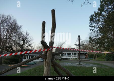 Geschlossener Spielplatz in der Baumschule wegen Coronavirus. Ein rot-weißes Absperrband verhindert den Eintritt. Es ist eine vorbeugende Maßnahme, die Ausbreitung zu stoppen Stockfoto