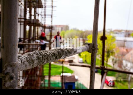 Gerüst ist gegen Gebäude platziert. Chef ist, beaufsichtigt von der Plattform über Baustelle. Stockfoto