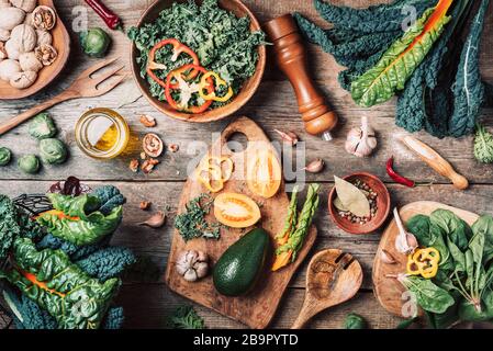 Orgnic gesunde vegane Zutaten zum Kochen. Draufsicht. Kopierbereich. Grünes Gemüse, Samen, Avocado, Nüsse, Kale, Gewürze, Salz, Holzutensilien auf wo Stockfoto