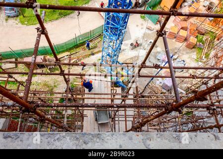 Das Gerüst wird gegen das Gebäude gestellt. Chef wird von der Holzplattform über der Baustelle beaufsichtigt. Stockfoto