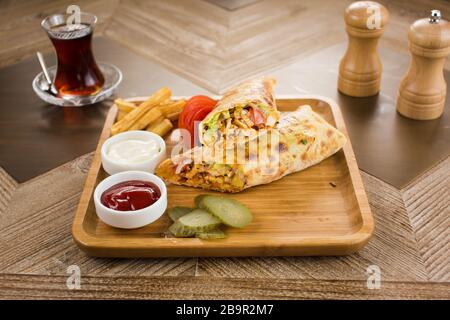 Shawarma Pita Brot mit gegrilltem Huhn, Schaurma Doner, frischem Gemüse und Sahnesauce auf hellem Stein oder Betongrund. Draufsicht mit Kopie Stockfoto