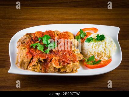 Traditionelle türkische iskender Kebap Döner mit speziellen roten Sauce und Joghurt in der Mitte mit gegrillten Tomaten und Paprika Huhn garniert serviert Stockfoto