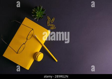 Gelber Bleistift, gelbe Notizbuchgläser, Stifte, Clippapier und gelbe ostereier auf schwarzem Hintergrund Stockfoto