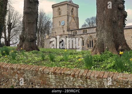 Englische Dorfkirche mit Turm und Frühlings-Blumenteppich auf dem Friedhof Stockfoto