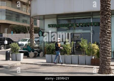 Beirut, Libanon. März 2020. Ein Mitglied der Öffentlichkeit in Beirut, das eine schützende Gesichtsmaske gegen die Ausbreitung von Kovid-19-Coronavirus-Infektionen trägt, läuft an einem geschlossenen Starbucks-Kaffee vorbei. Credit: amer ghazzal/Alamy Live News Stockfoto