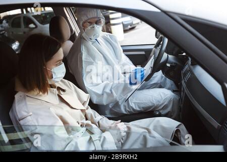 Arzt in Virus-Schutzanzug verhört Frau Patienten Stockfoto