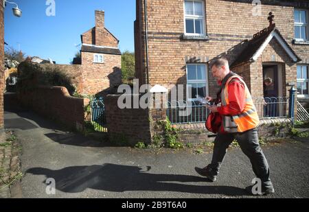 Der Postzusteller Matt liefert Post im Dorf Ironbridge in Shropshire, während seine Kunden zu Hause bleiben müssen, nachdem Premierminister Boris Johnson Großbritannien in Sperrstellung versetzt hat, um die Ausbreitung des Coronavirus einzudämmen. Stockfoto