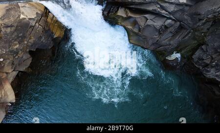 Wasserfall von oben nach unten. Von oben auf den Bach fließt Wasser über die Steine. Felsiger Bergwasserfall. Landschaft Berge felsiger Kaskadenfluss Stockfoto