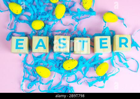 Wort Ostern auf Holzwürfeln und umgeben mit mehreren Eierdekorationen als festliche Oster-Hintergrundkomposition Stockfoto